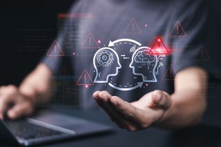 © Pakin - Adobe Stock.com Foto: Abstrakte Köpfe mit Warndreiecken über Hand von einer Person